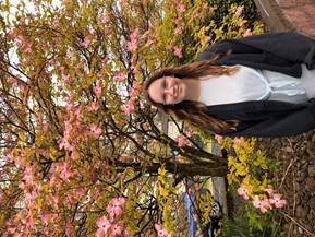 Carly standing outside in front of a tree