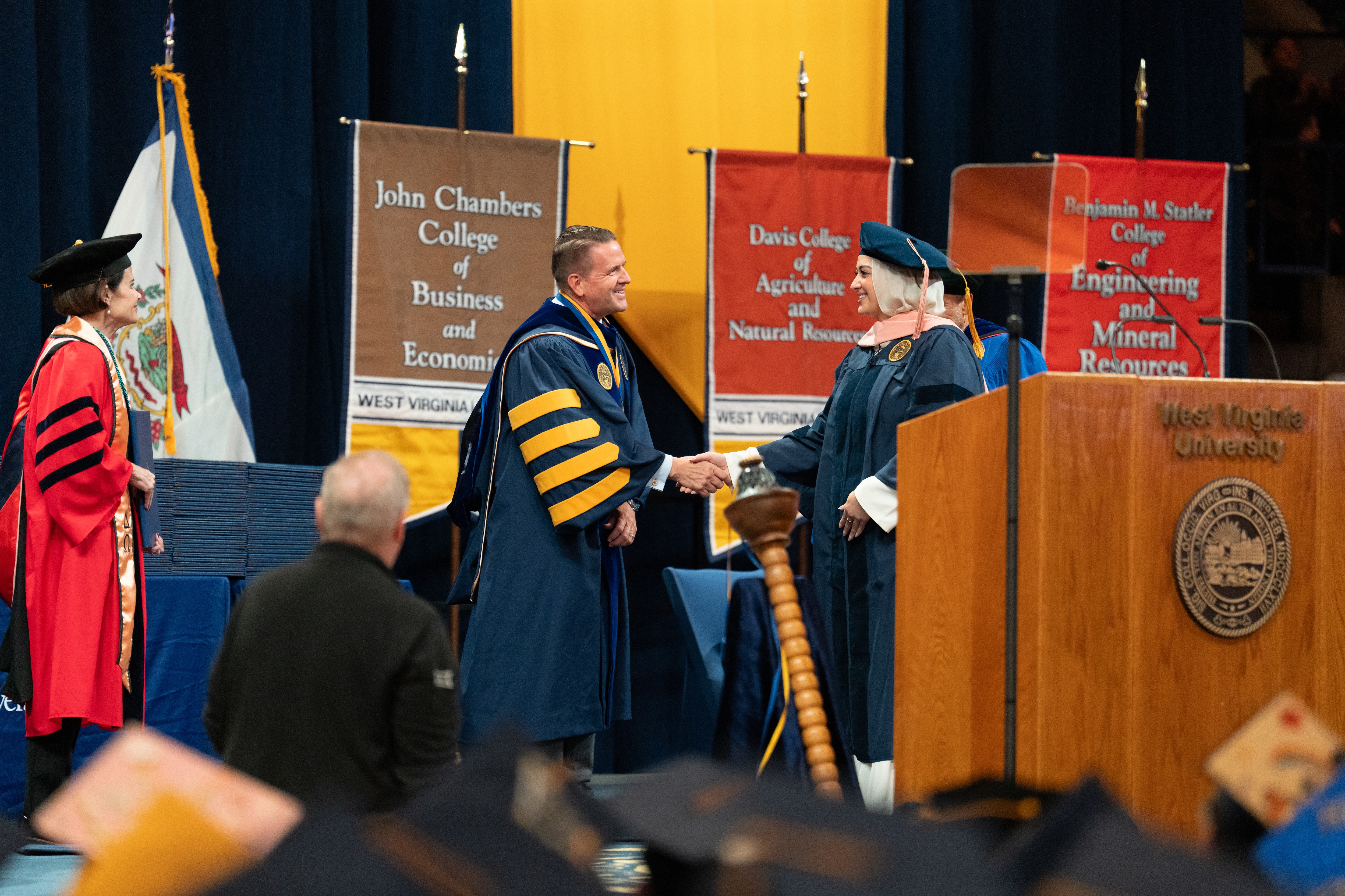 Student shaking hands with President Benson as she crosses the Commencement stage. 