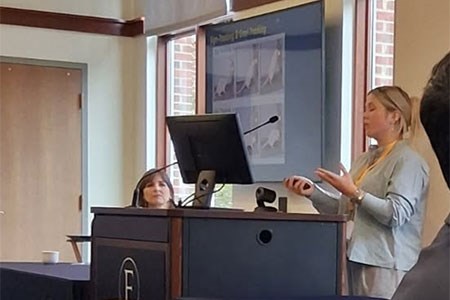 A speaker addressing a room from the podium.